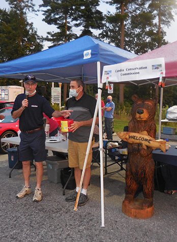 L to R: Dean Young selects the winning raffle ticket for the carved bear, Leon Austin, and the bear.